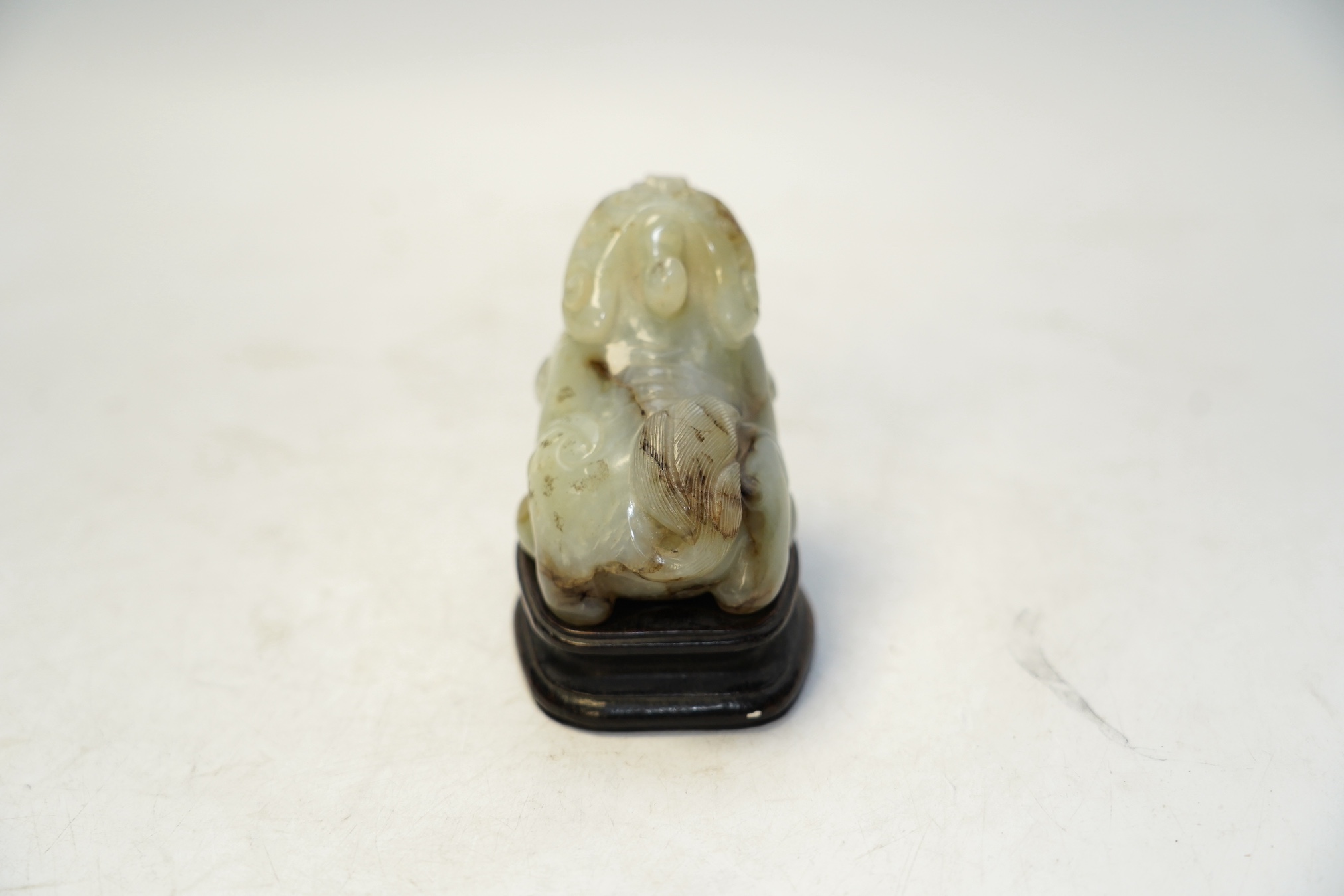 A Chinese carved jade ‘lion dog’ and stand, 8cm tall. Condition fair to good.